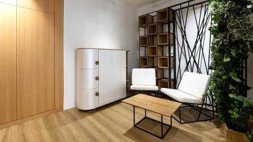 This clean, contemporary interior demonstrates how the custom-designed T-DESIGN sideboard integrates seamlessly into a modern living space. The finely milled curved fronts, natural oak details, and understated color palette create an elegant aesthetic while providing practical storage.  The sideboard is complemented by pieces from the TorTer LOFT furniture collection, including distinctive steel-frame lounge chairs, a minimalist coffee table, and an open shelving room divider. Together, these elements creat