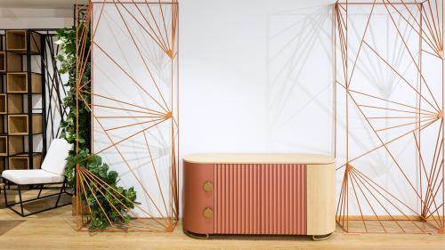 Die kompakte T-DESIGN Kommode kombiniert eine kupfer-roséfarbene Front mit natürlicher Eiche und Messingdetails. Die dekorativen REZES BANDA Raumteiler ergänzen das Möbelstück und schaffen ein modernes, harmonisches Interior.
